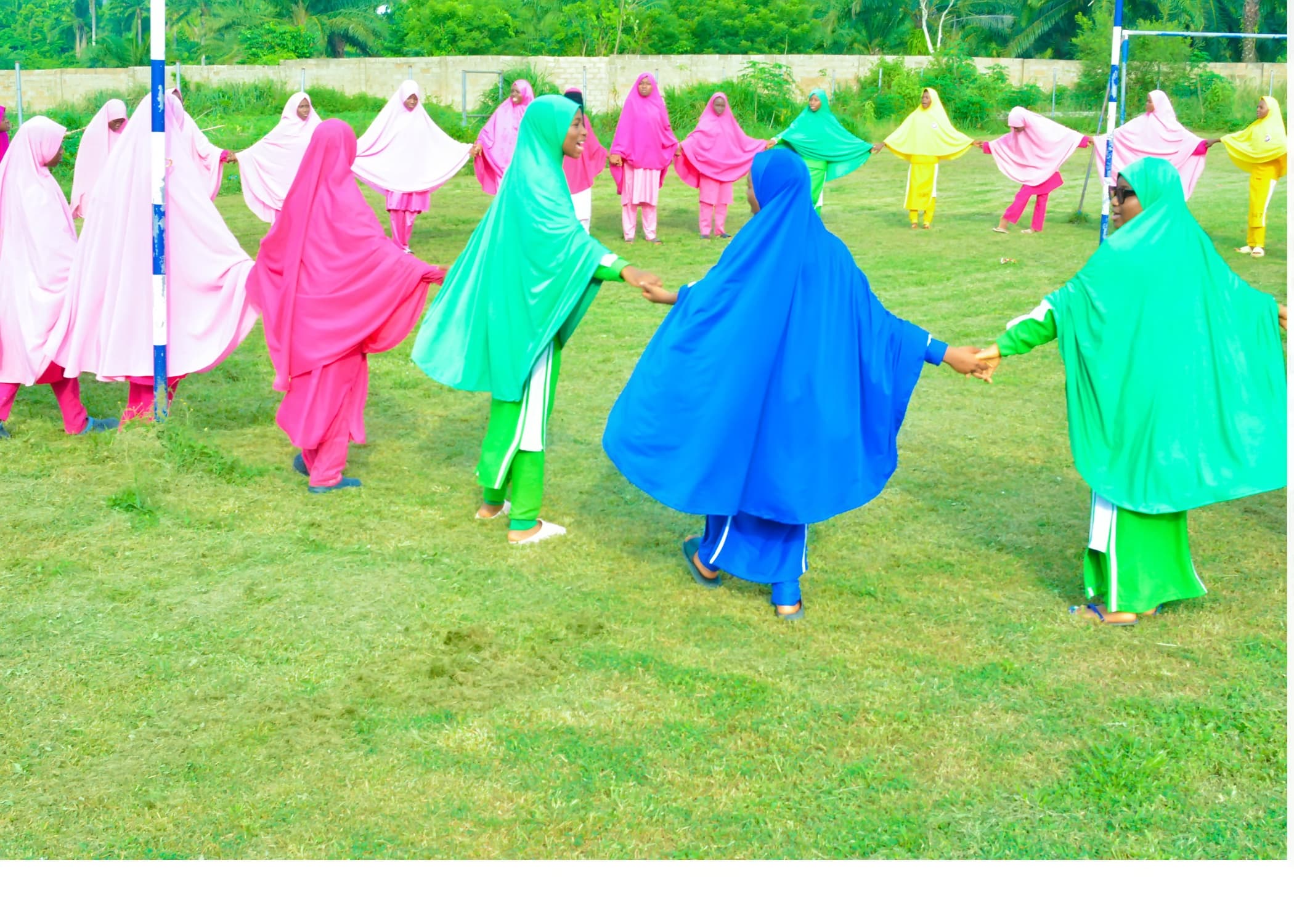 Inaayatullah students in colourful sports house uniforms taking part in a team activity on the field