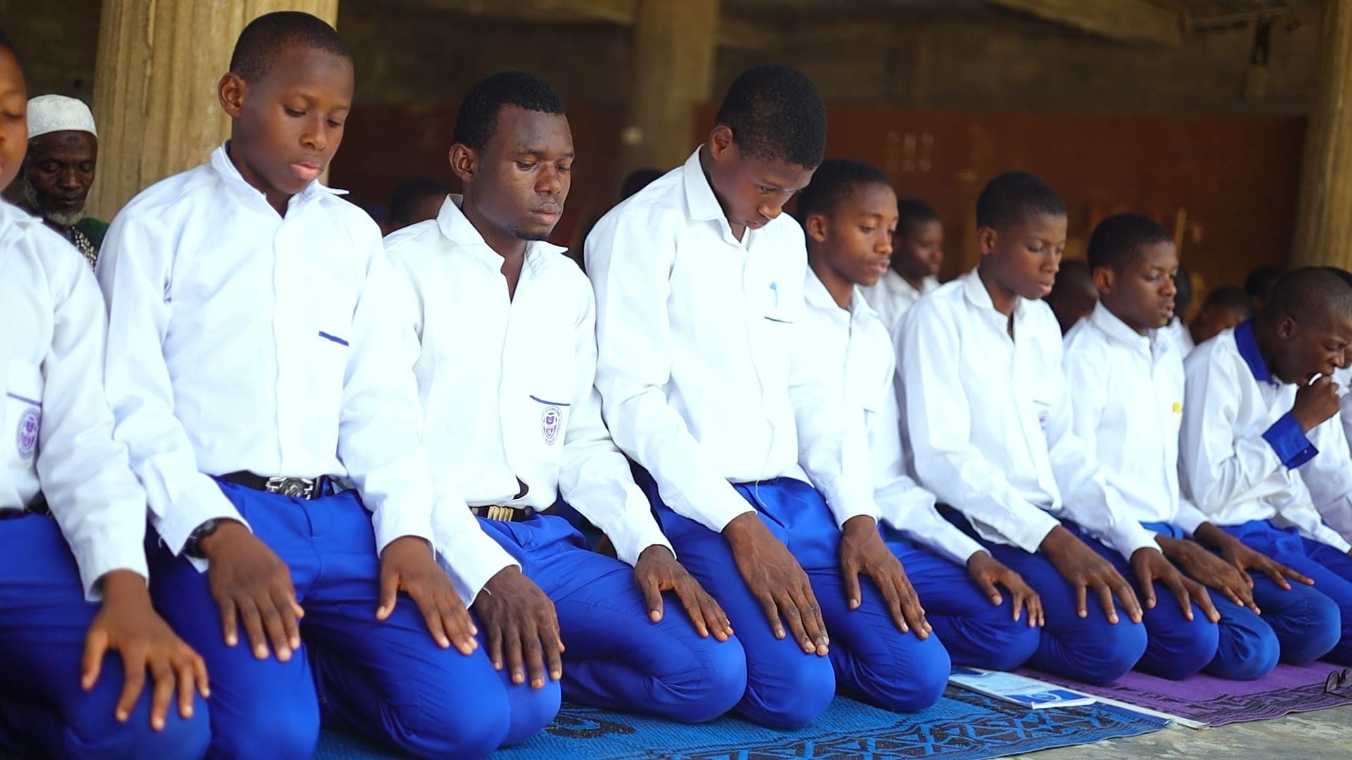 Boys in white shirts praying together in rows