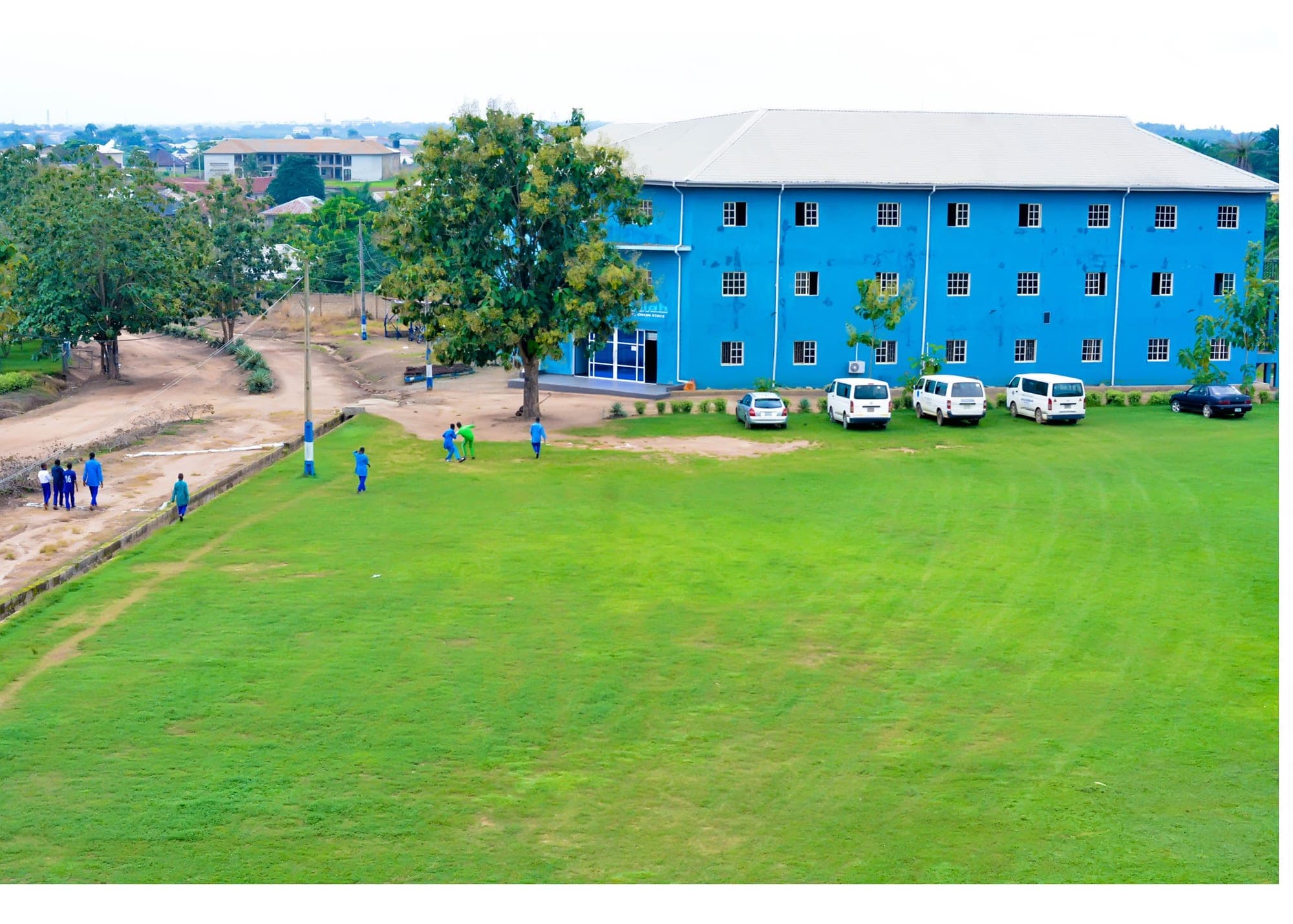 The blue Academy building beside a wide green lawn