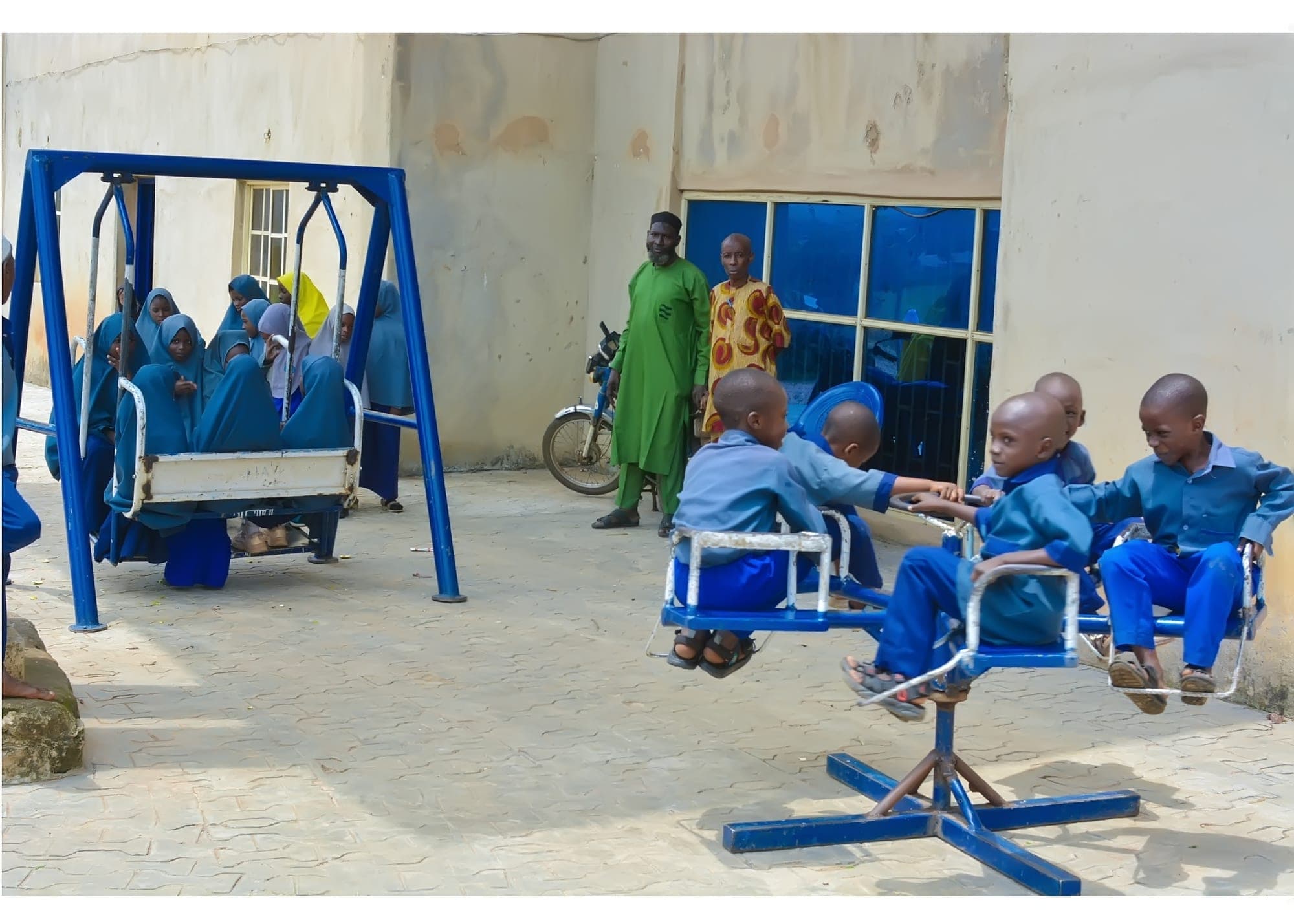 Pupils playing on a swing and a roundabout in the school courtyard
