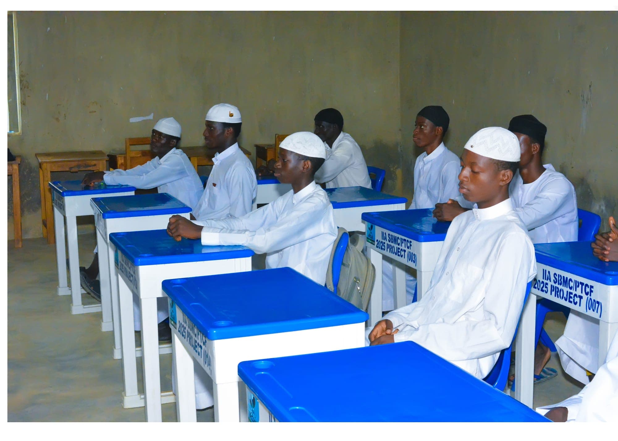 Rows of senior boys at blue desks listening attentively in a classroom