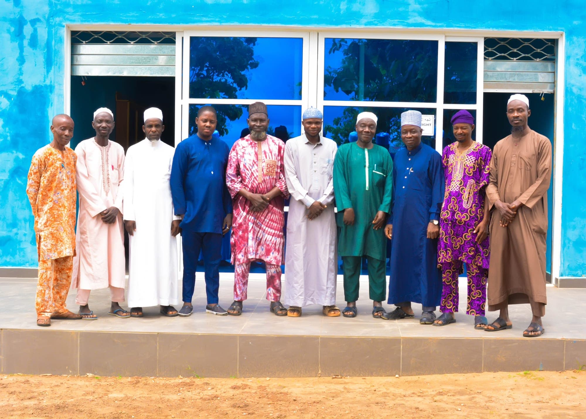 Male members of staff standing together in front of the Academy building